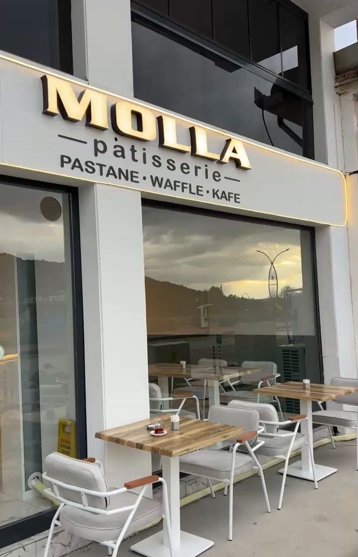 Molla Patisserie’nin dış cephesi: ışıklı tabela ve kaldırımdaki masalar