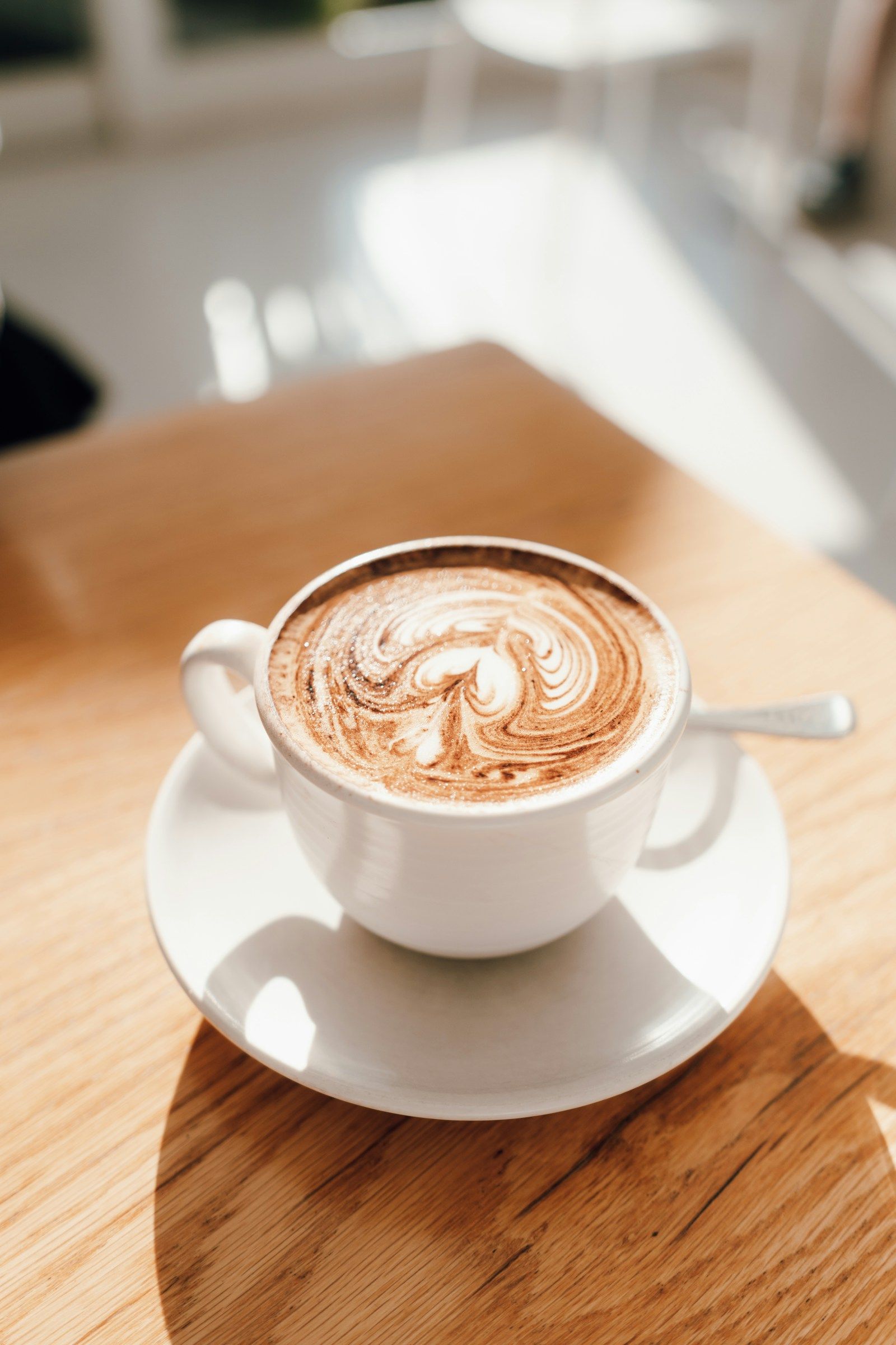 Ahşap masada, köpüğü desenli bir fincan latte