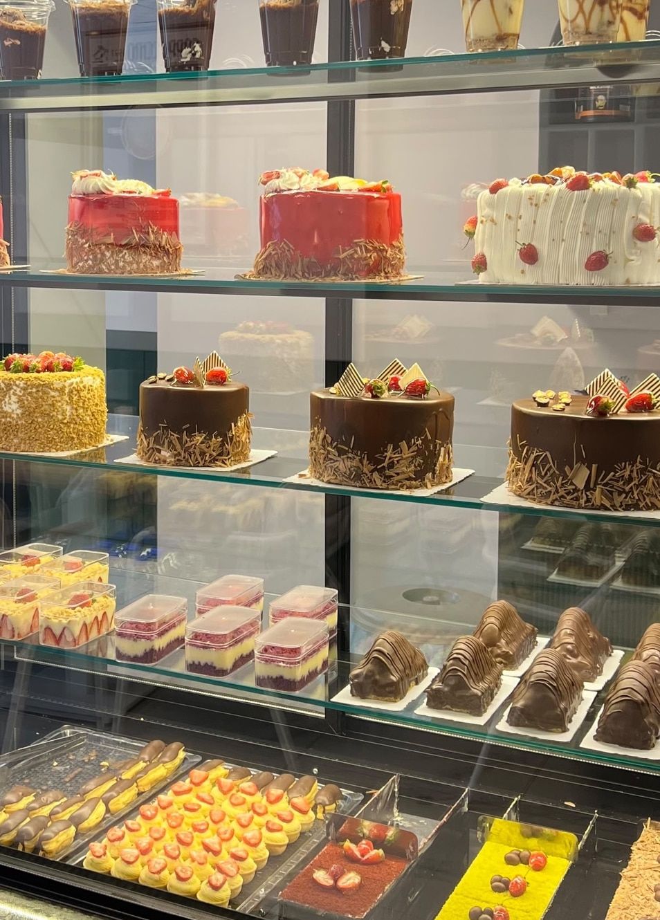 Molla Patisserie vitrininde raf raf yaş pastalar: çikolatalı, meyveli ve kremalı pastalar; alt raflarda küçük tatlılar