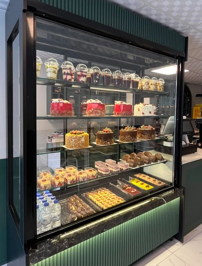 Molla Patisserie’nin pasta vitrini: raflarda yaş pastalar, bardakta tatlılar ve küçük tatlılar