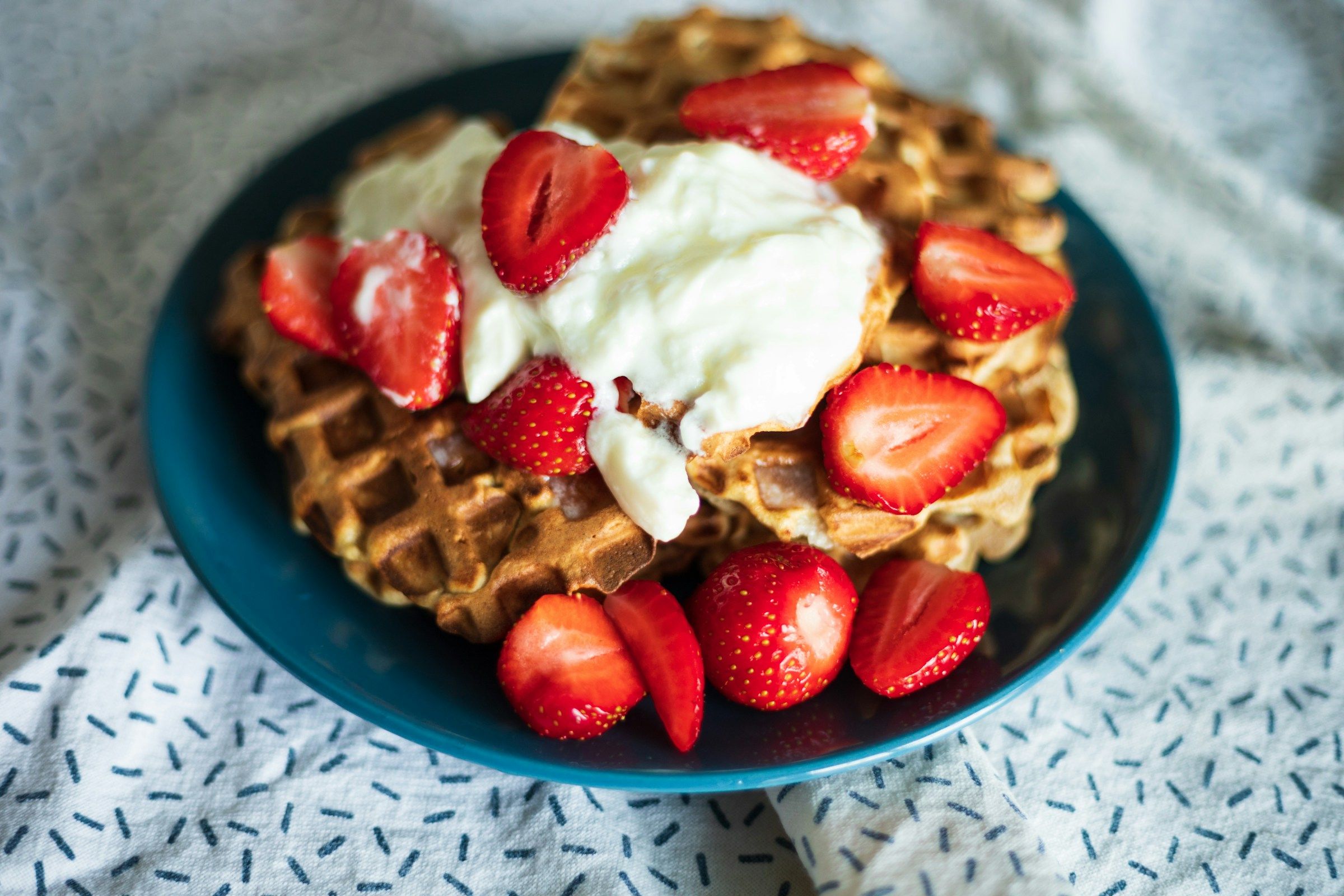 Çilek ve kremayla süslenmiş waffle tabağı
